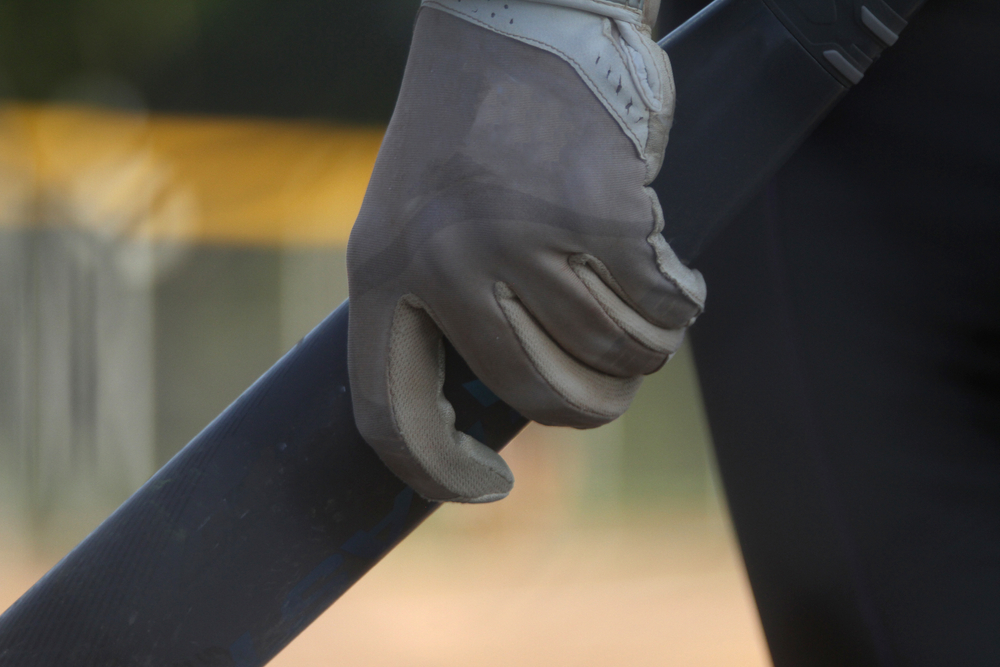 A softball player grips her bat as she stands in the on-deck circle